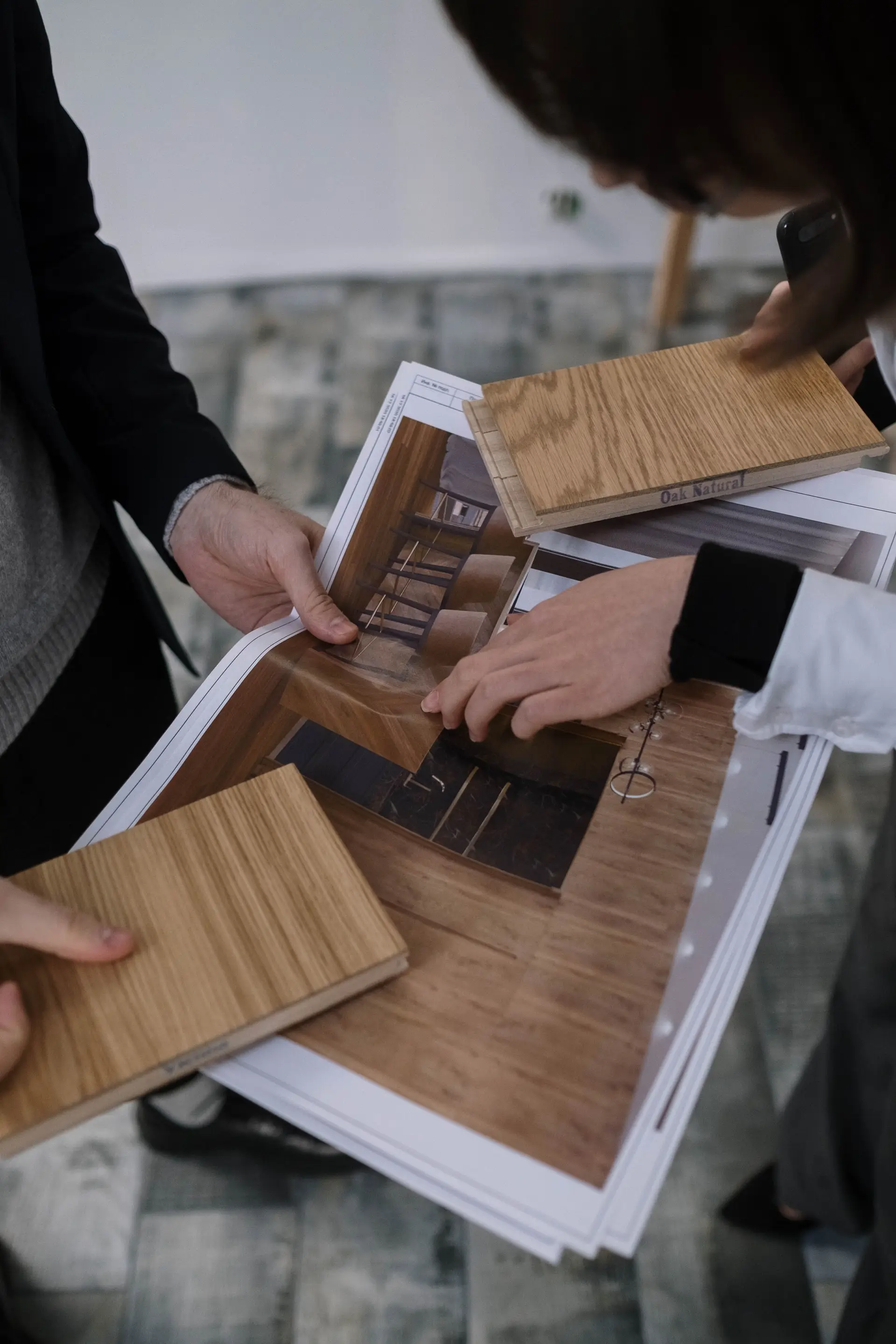 Design team reviewing timber samples and architectural floor plans in studio