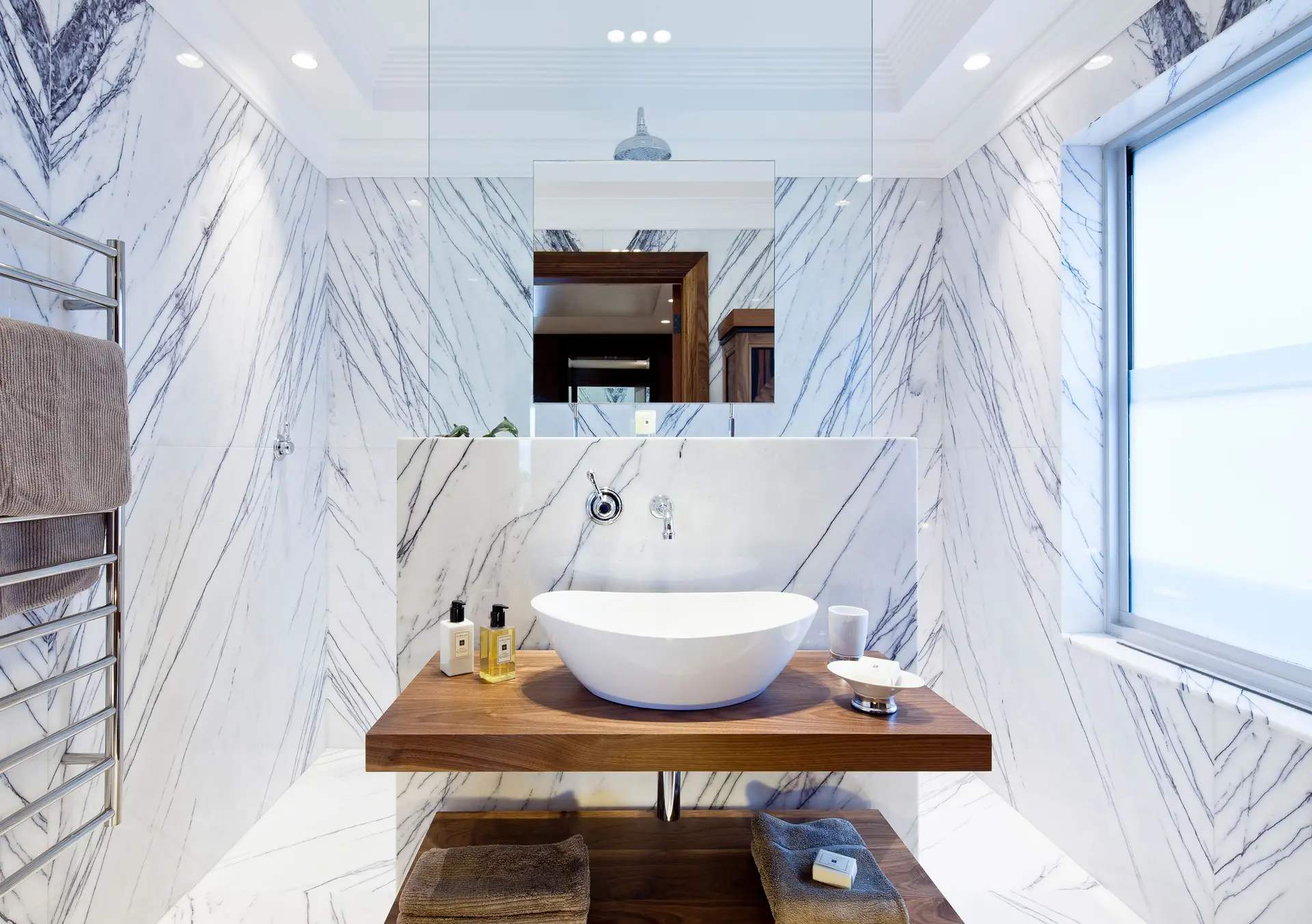Bookmatched travertine bathroom suite with brushed patinated bronze fixtures
